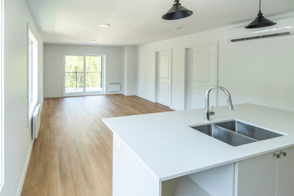 Cuisine moderne à aire ouverte avec îlot et comptoir en quartz dans un condo neuf à Sherbrooke - Gestion Floria