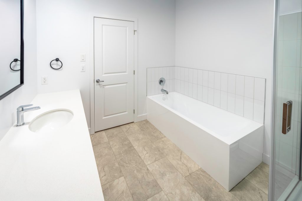 Salle de bain moderne et épurée avec grand bain autoportant et douche vitrée dans un condo neuf à Magog - Gestion Floria