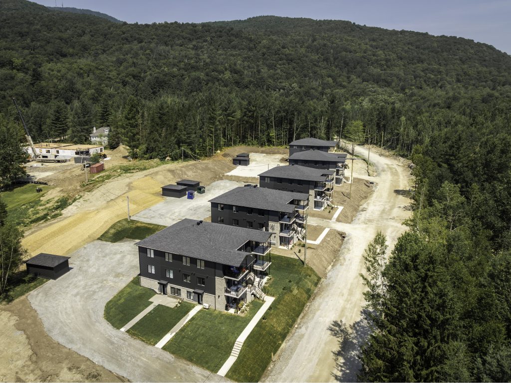 Vue aérienne d'un immeuble de condos modernes au pied de la montagne à Magog - Gestion Floria